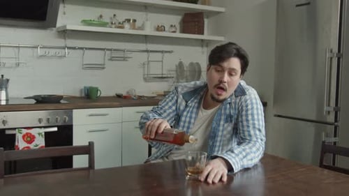 Man Drinking Alcohol Sitting at Kitchen Table