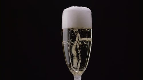 Glass of Champagne with a Rotating Bubbles Inside. Black Background. Close Up