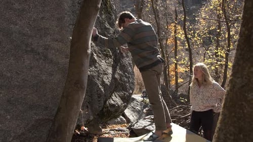 Young Adult Climber Bouldering Outdoors with Assistant
