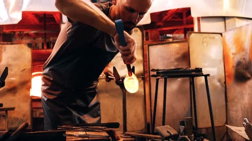 Glassblower Shaping Molten Glass in Workshop