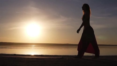 Silhouette of a Fit Woman Near the Water Unfolds the Yoga Mat Preparing Doing Yoga or Pilates
