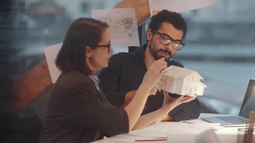Multiethnic Male and Female Architects Discussing House Maquette in Office