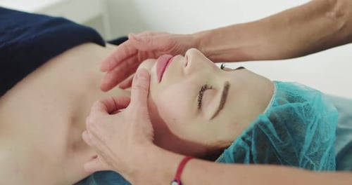 Young Beautiful Caucasian Woman Lying on Spa Bed Get Facial Massage Treatment