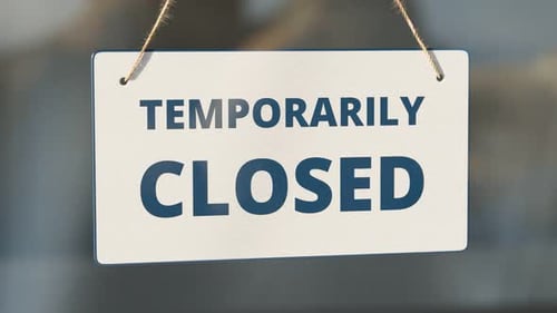 Temporarily closed due to COVID-19. Zoom in white close sign on the glass door.