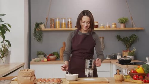 Woman Sifting Flour in Kitchen