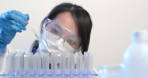 Scientist Using Pipette to Add Liquid to Test Tubes
