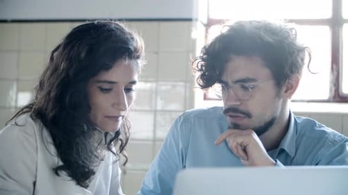 Front View of Smiling Young Colleagues Looking at Laptop