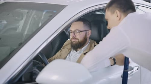 an Adult Man Sits in the Salon of a New Car in a Dealership