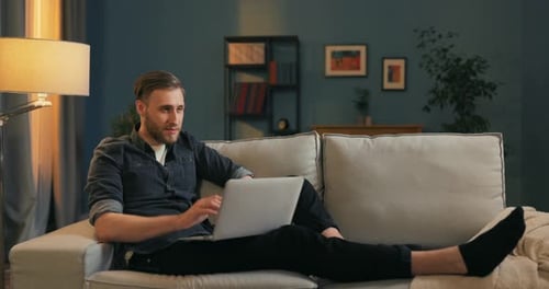 Smiling Boy Works Remotely in His Own Living Room on His Couch Holds His Laptop
