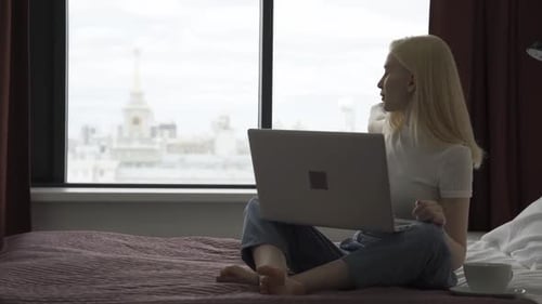 Woman Using Laptop in Sunny City Apartment