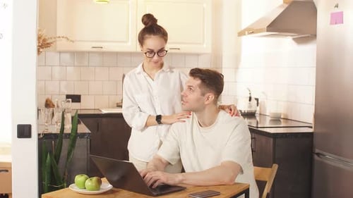 Couple Working on Laptop Together at Kitchen Table