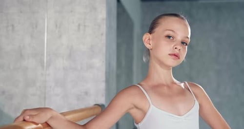 Graceful Girl Stands Near Wooden Barre and Large Mirror