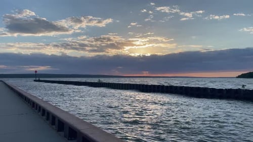Schöner Sonnenuntergang über dem See Orange Sonne Blaues Wasser Bewölkter Abend mit Lichtstrahlen auf der Promenade