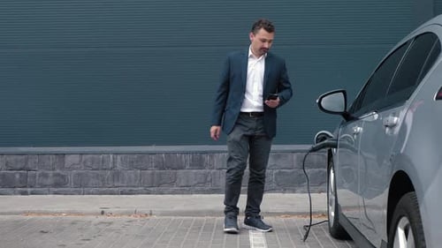 Man Unplugs Electric Car at Charging Station