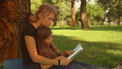 Mother and Daughter Reading Together in a Park