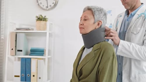 Doctor Fitting Cervical Collar on Senior Woman