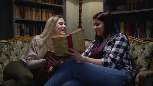 Two Smiling Women Reading Together Indoors