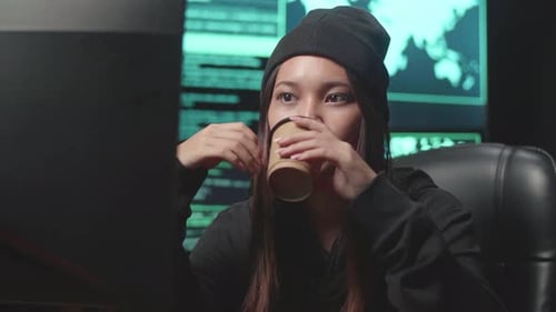 Asian Woman Hacker Using Computer Hacking And Drinking Coffee, Code On Multiple Computer Screens