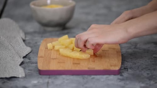 Hands Slicing Pineapple Rings on Cutting Board