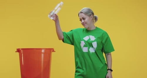 Woman Recycling Plastic Bottle into Red Bin