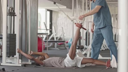 Junger Mann macht Rehabilitationsübungen mit persönlichem Lehrer