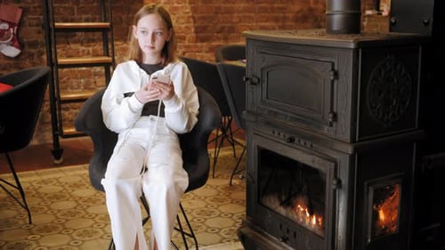 Teen Using Phone near Cozy Fireplace