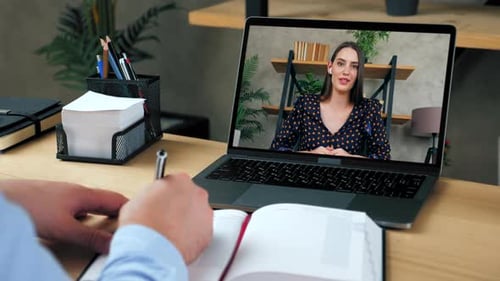 Man Video Conferencing With Woman and Taking Notes