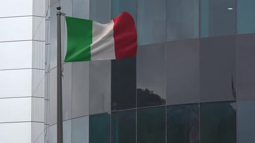 Italian Flag Waving on Flagpole Against Modern Building