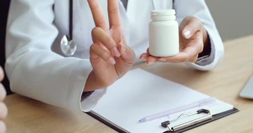 Close-up of Female Hands of Medical Specialist Showing Bottle of Tablets To Man To Patient, Showing