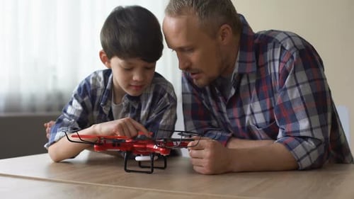 Father and Son Play with Drone at Home