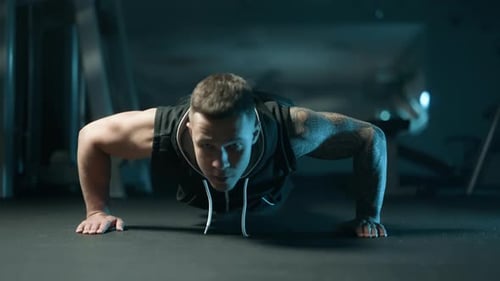 A Handsome Young Muscular Sportsman is Doing Exercise on a Fitness Machine in the Gym