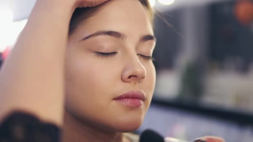 Professional Makeup Artist at Work Closeup View of Female Hands Applying Facial Powder on Young