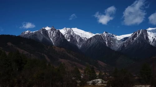 Time lapse of massive mountains with snow on the top and a clouds are moving on blue sky