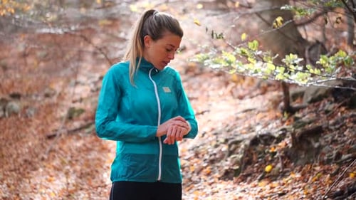 Female jogger having a break from exercising looking on smartwatch