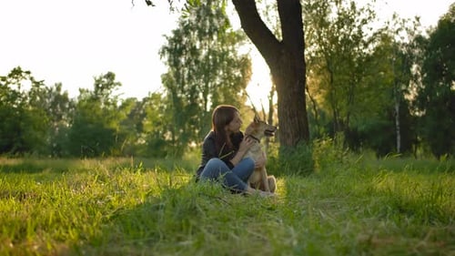 Woman Cuddling Dog in a Sunny Green Meadow