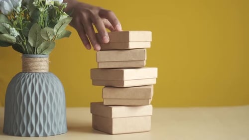 Hand Removing Small Brown Boxes from Stack