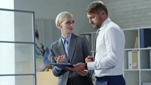 Coworkers Discussing Document on Clipboard
