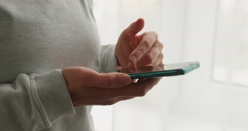 Smartphone in the cropped hands of a woman. Using a mobile phone, close-up.