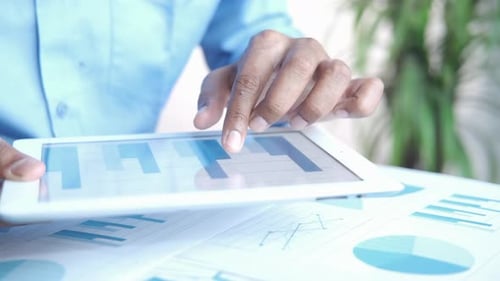 Man's Hand Working on Digital Tablet at Office Desk Using Self Created Chart