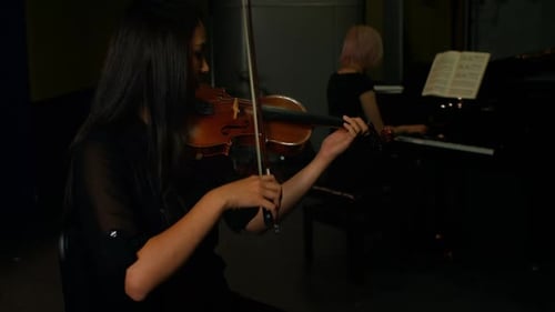 Woman Plays Violin While Pianist Accompanies
