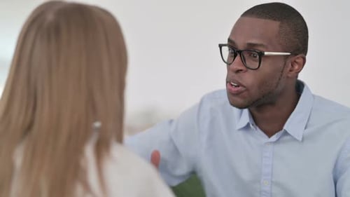 Vue arrière d'un couple métisse ayant une conversation sur un canapé