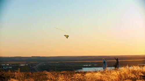 Young Family Playing with Kite on the Field on Sunset - Father Holding the Rope of Kite