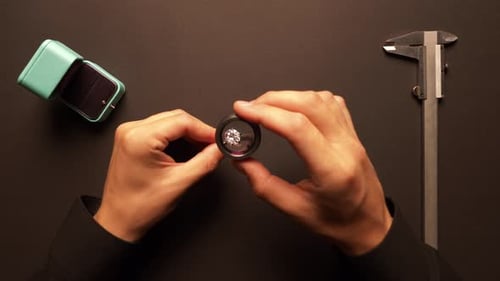 Close Up Hands Inspecting Diamond Ring With Loupe