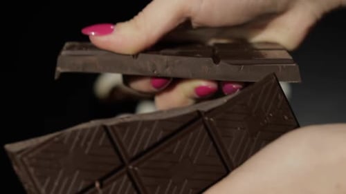 Woman Breaks Black Chocolate Bar