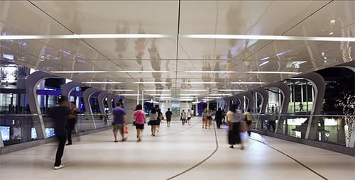 Urban Pedestrians Traverse Modern Elevated Walkway at Night