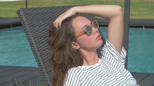 Woman Relaxing on Deck Chair by Swimming Pool