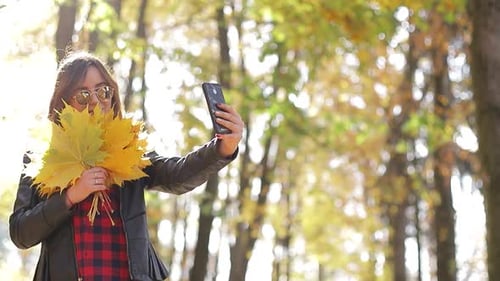 Beautiful teenage girl taking Selfie on smartphone outdoors in Park on Sunny autumn day