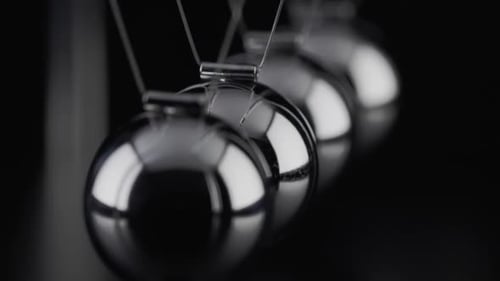 The balls of a Newtons Cradle colliding in slow motion