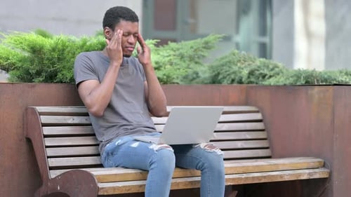Young Adult Works on Laptop, Gets a Headache