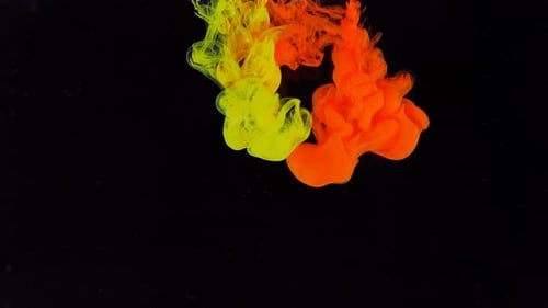 Stream of Red and Yellow Paint Dissolves in a Transparent Space on a Black Background